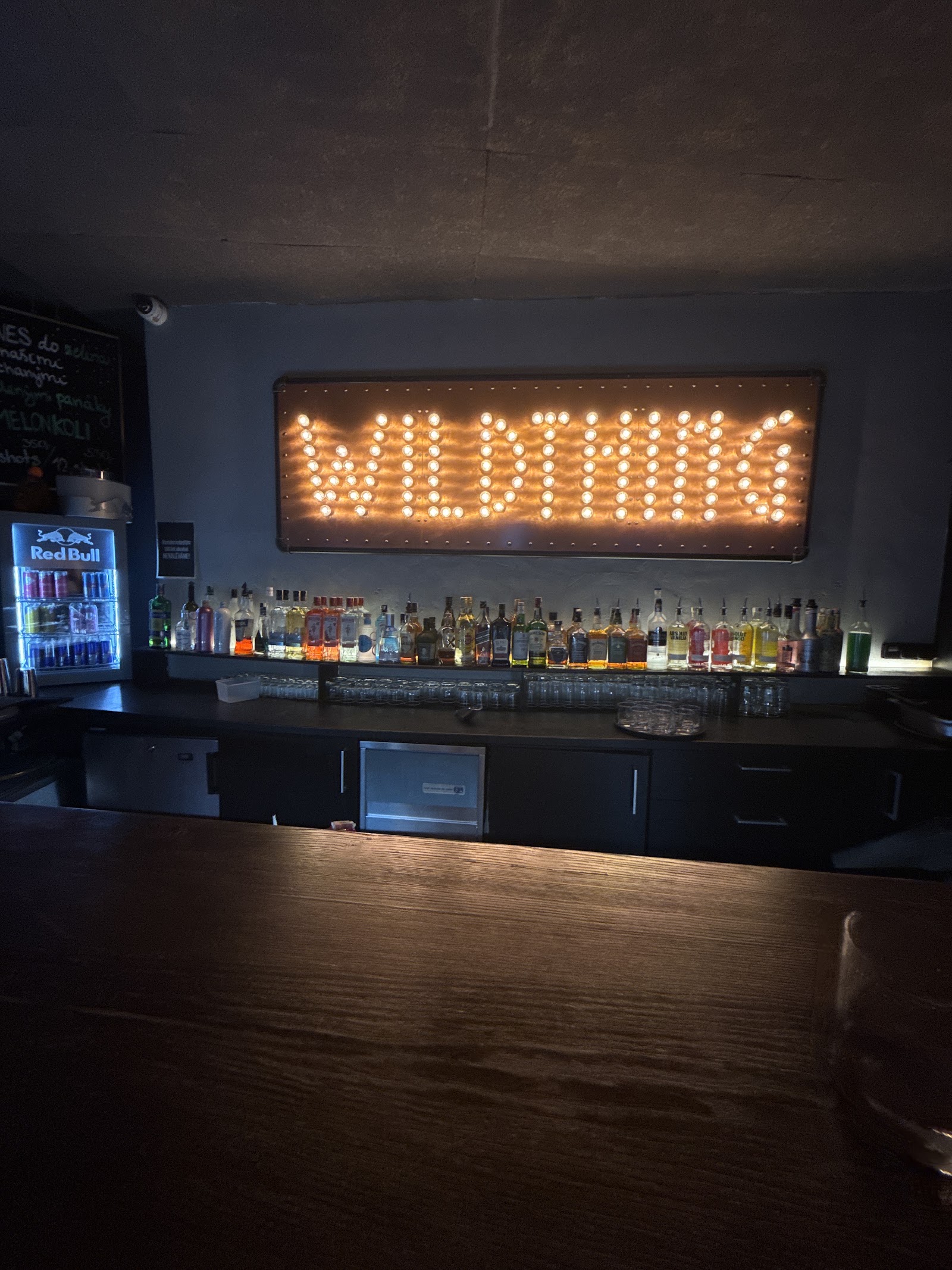 Osvětlený nápis WILD THING nad plným barem.